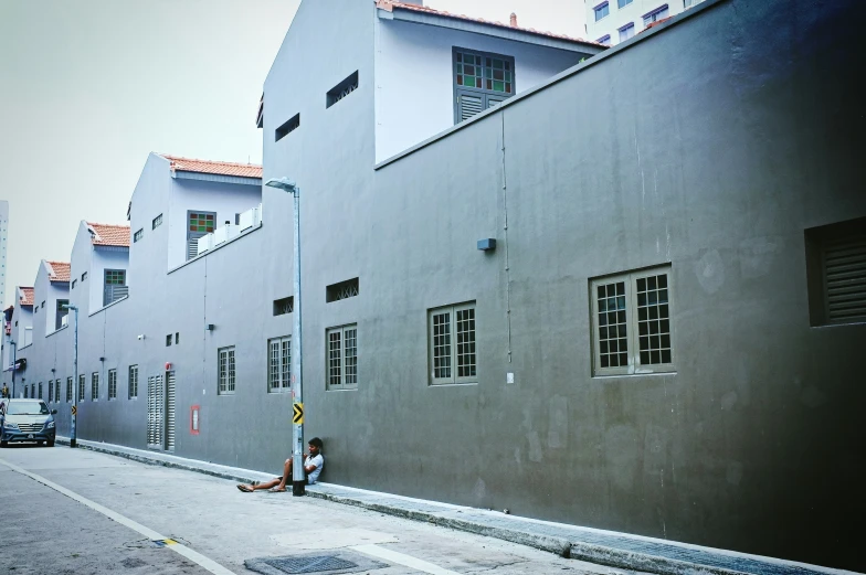 a person sitting next to a street near a building