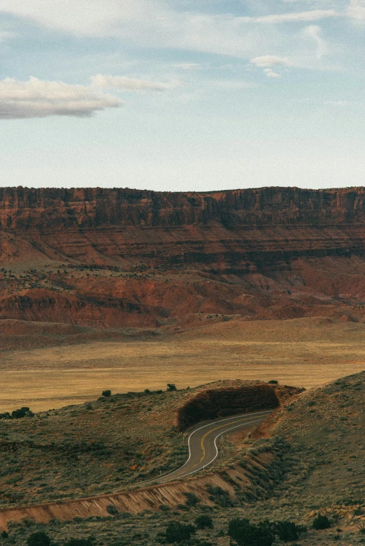 an open plain with hills, bushes, and a road