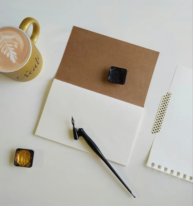 the flat - tip of a writing tool sits next to the envelope and an ink brush