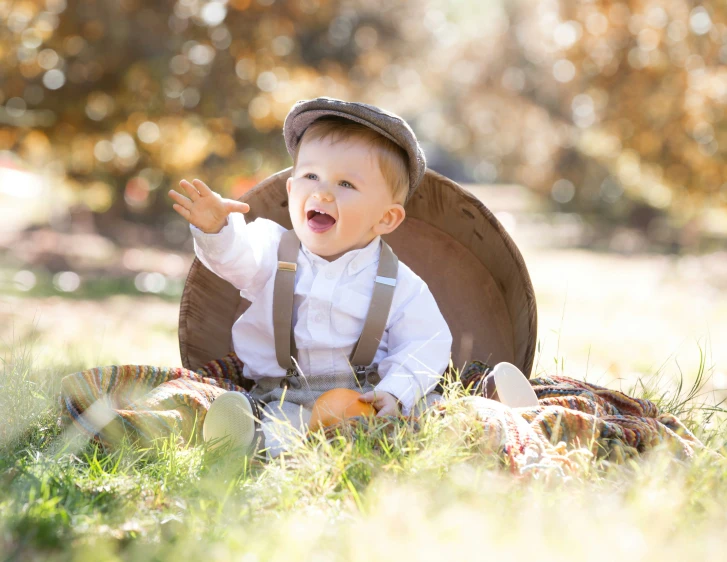 a little boy is sitting in a wooden chair on the grass