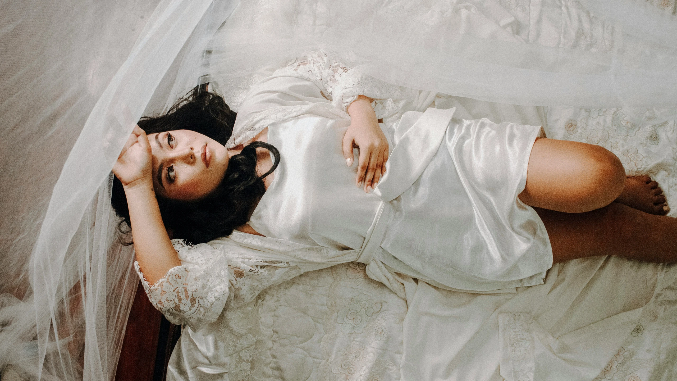 a young lady is sleeping on the bed dressed in white