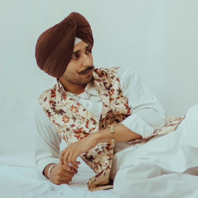 an indian man is sitting on a white bed