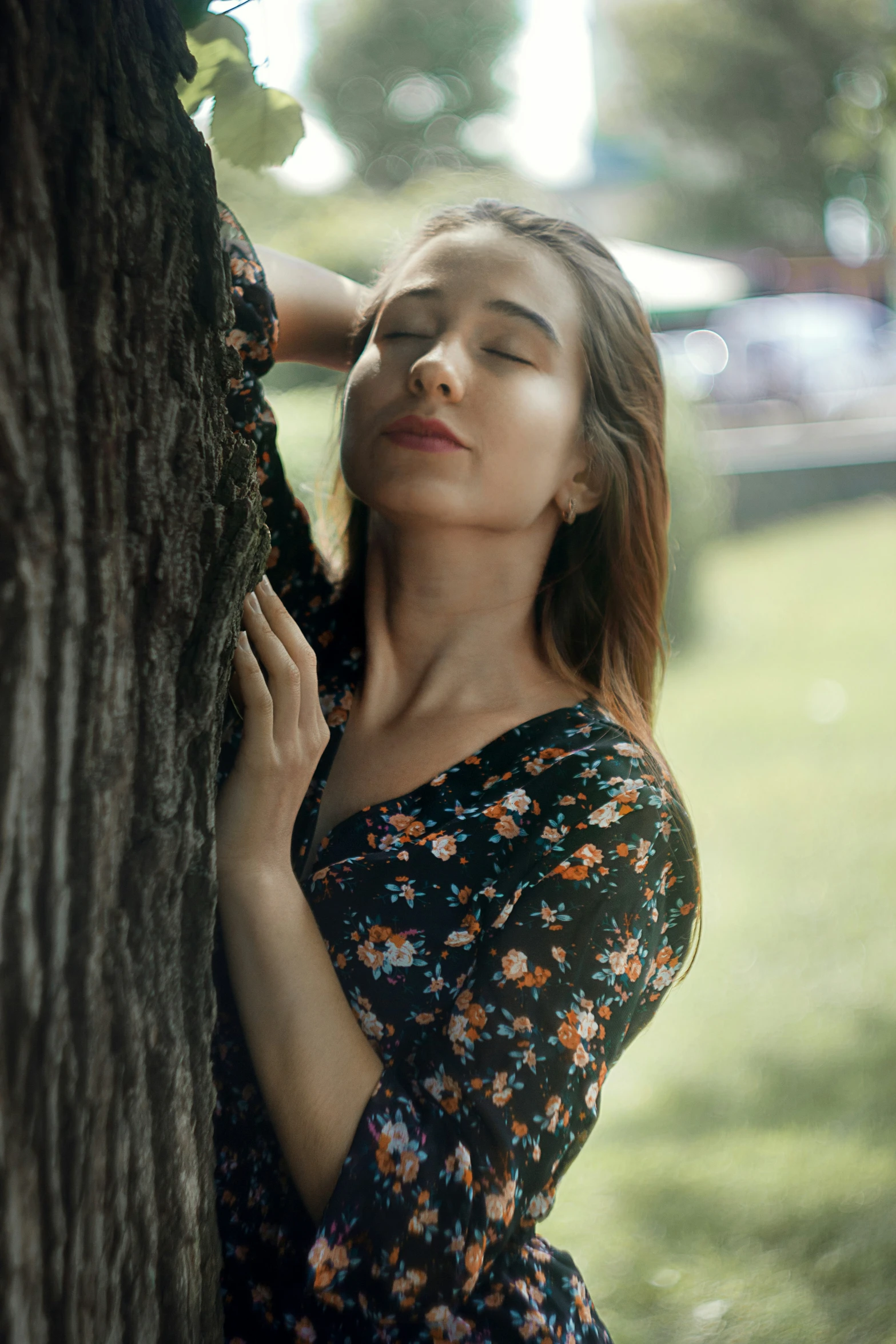 a woman with her eyes closed leans on a tree