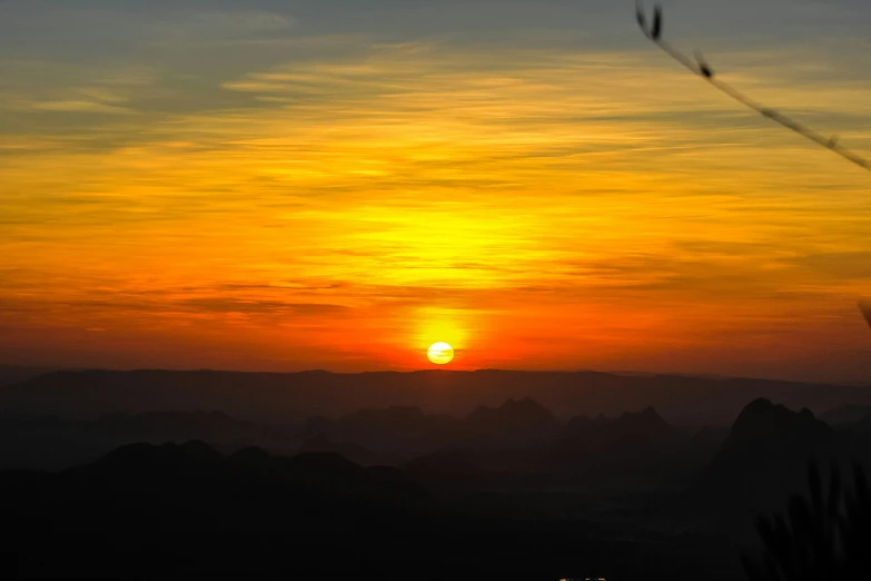 the sun setting in the sky over mountains