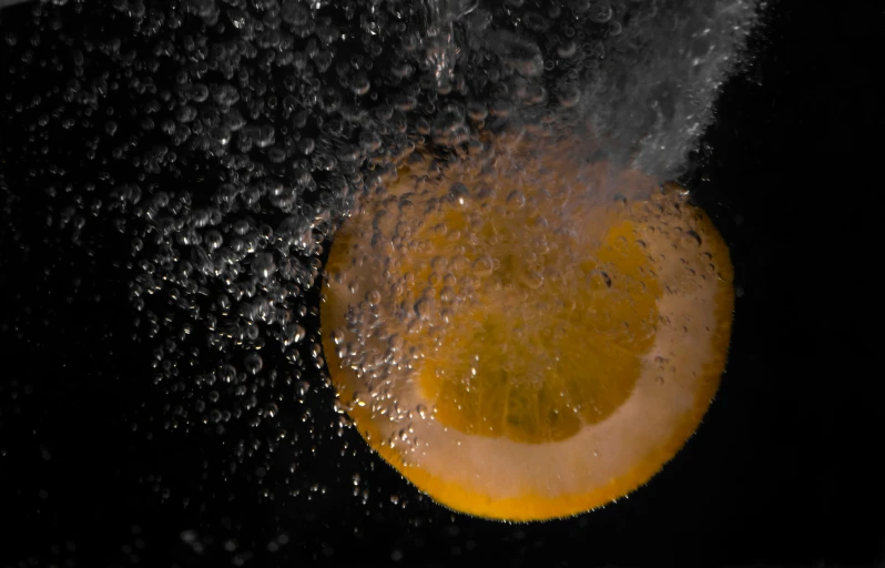 an orange is being splashed with water on a black background