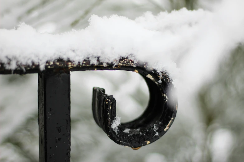 a metal bench with snow on the top of it