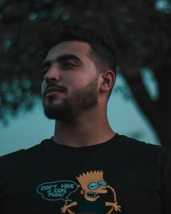 the man is standing near some trees looking away