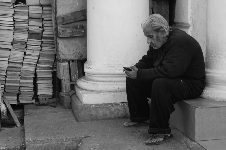 an old man is sitting down on his phone