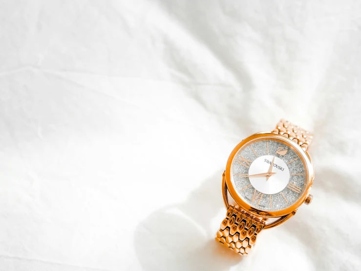 a watch with a gold metal celet and round face