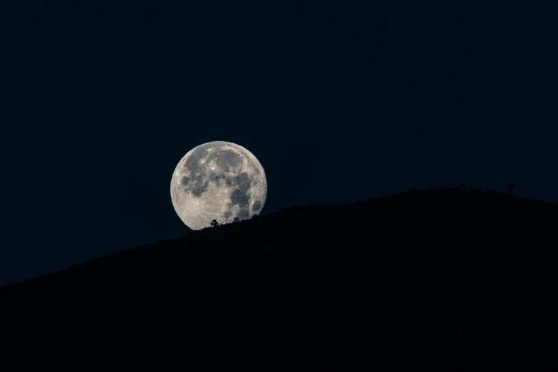 the full moon shines bright above the mountain and trees