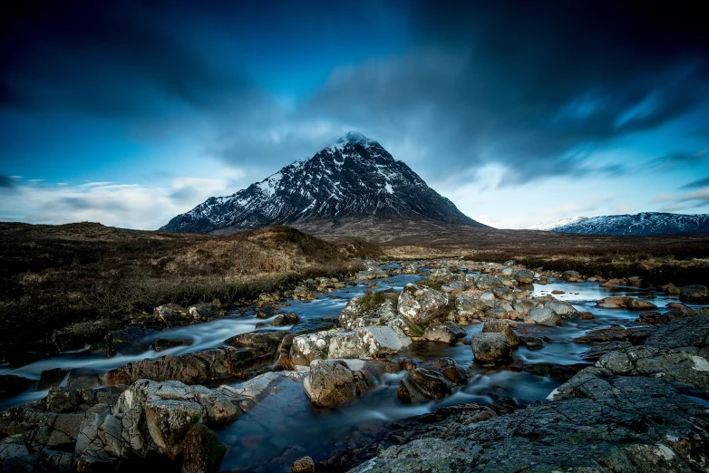 a snowy mountain sits in the distance, with river moving through it