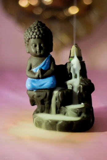 the little statue is holding the string of the incense