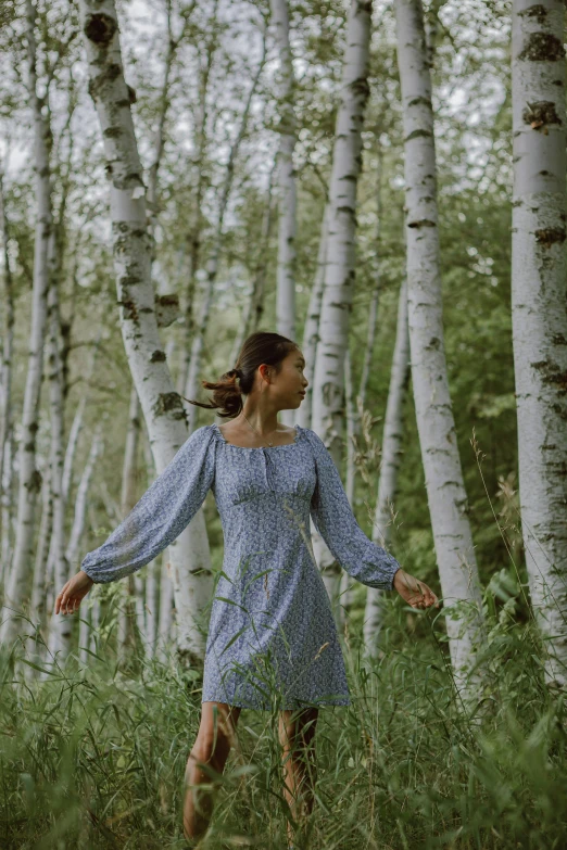 a woman standing in tall grass next to trees