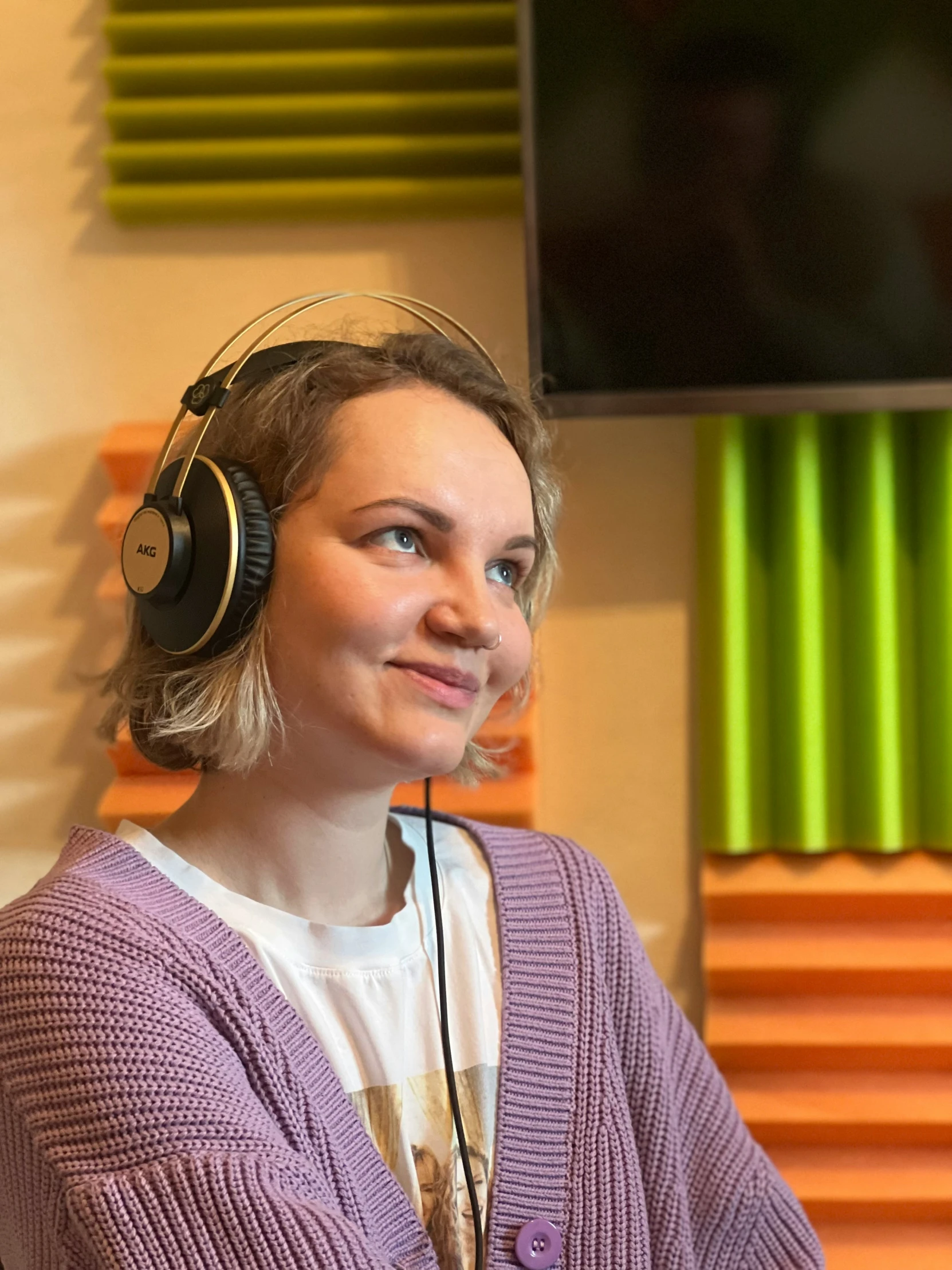 a beautiful woman wearing headphones sitting in front of a monitor