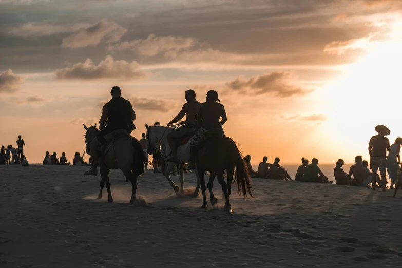 a group of people are riding horses in the sand