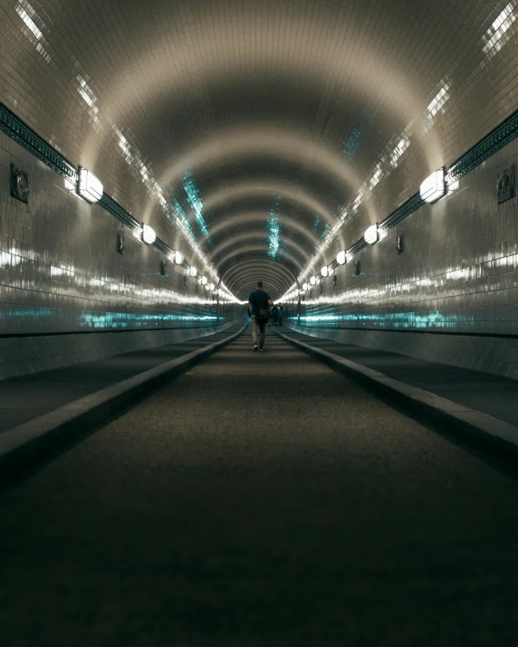 an illuminated tunnel at night with some people walking in it