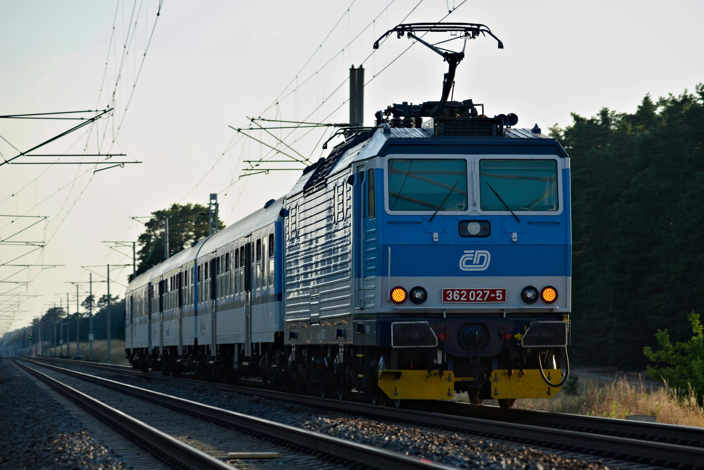 a blue and white train driving down the train track