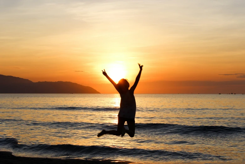 person jumping off surfboard at sunset near the ocean