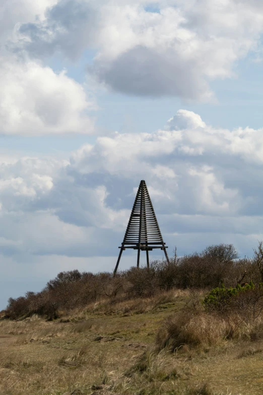 a tall wooden structure on top of a grass hill