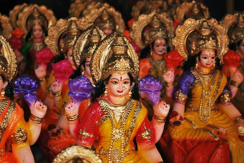 deities with elaborate clothes sit and sing during a festival