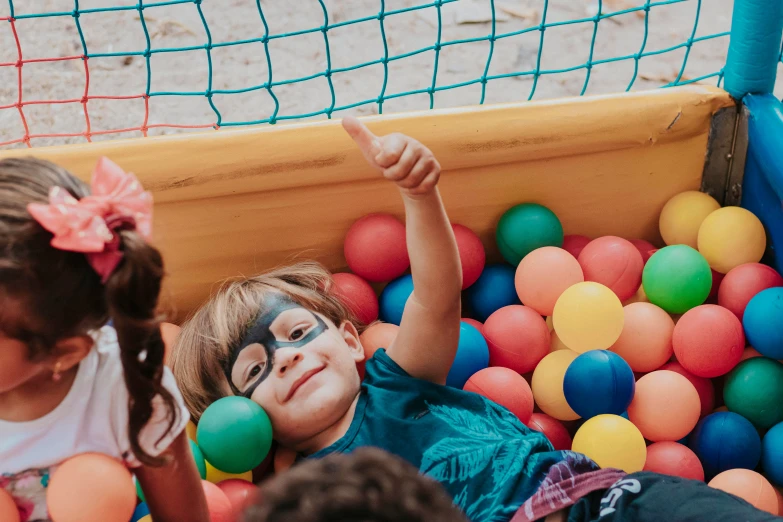 two girls are in a ball pool with the help of balls on her face