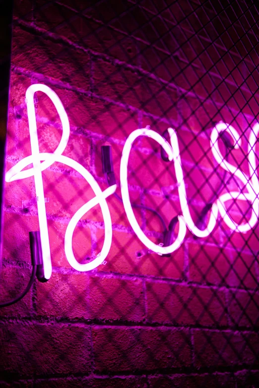 a neon pink sign that says boss next to a brick wall