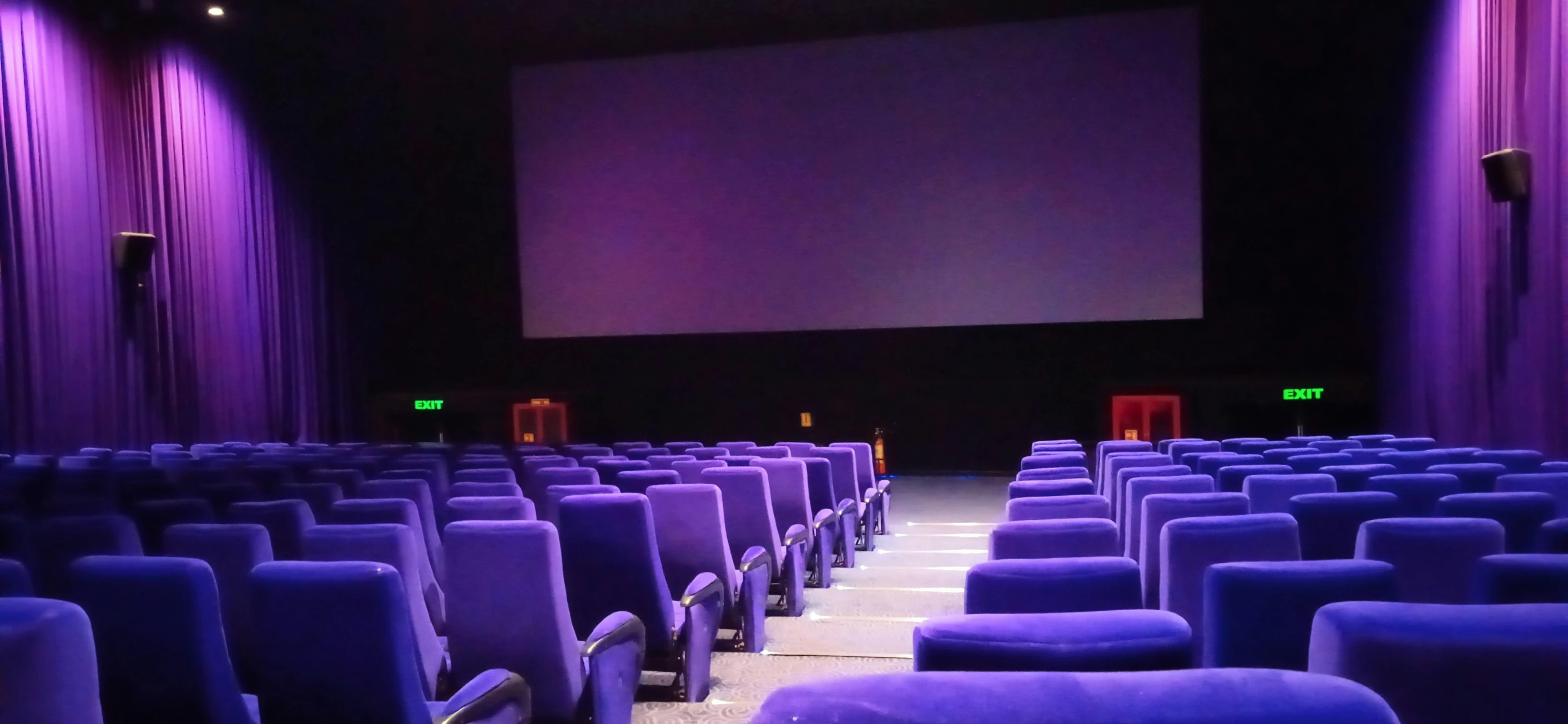 a row of blue seats with a large screen