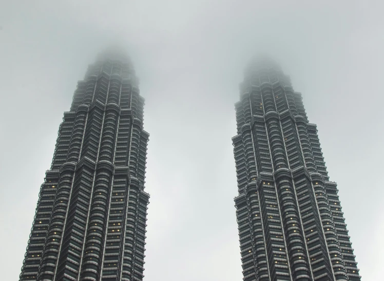 twin petrona towers in fog and rain seen from the ground