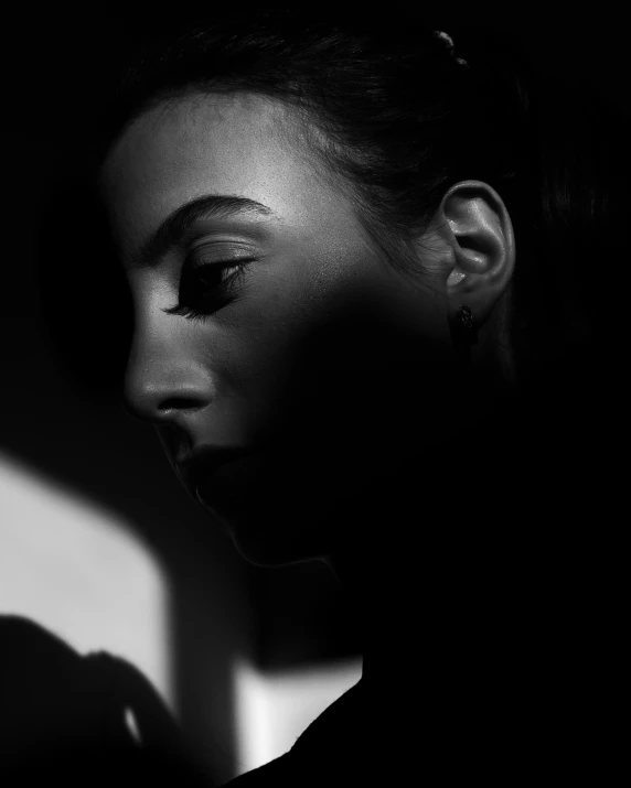 a woman in dark with a black shirt and earrings