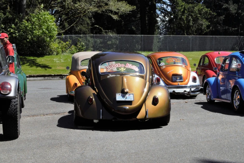 five old model cars parked in a line in a parking lot