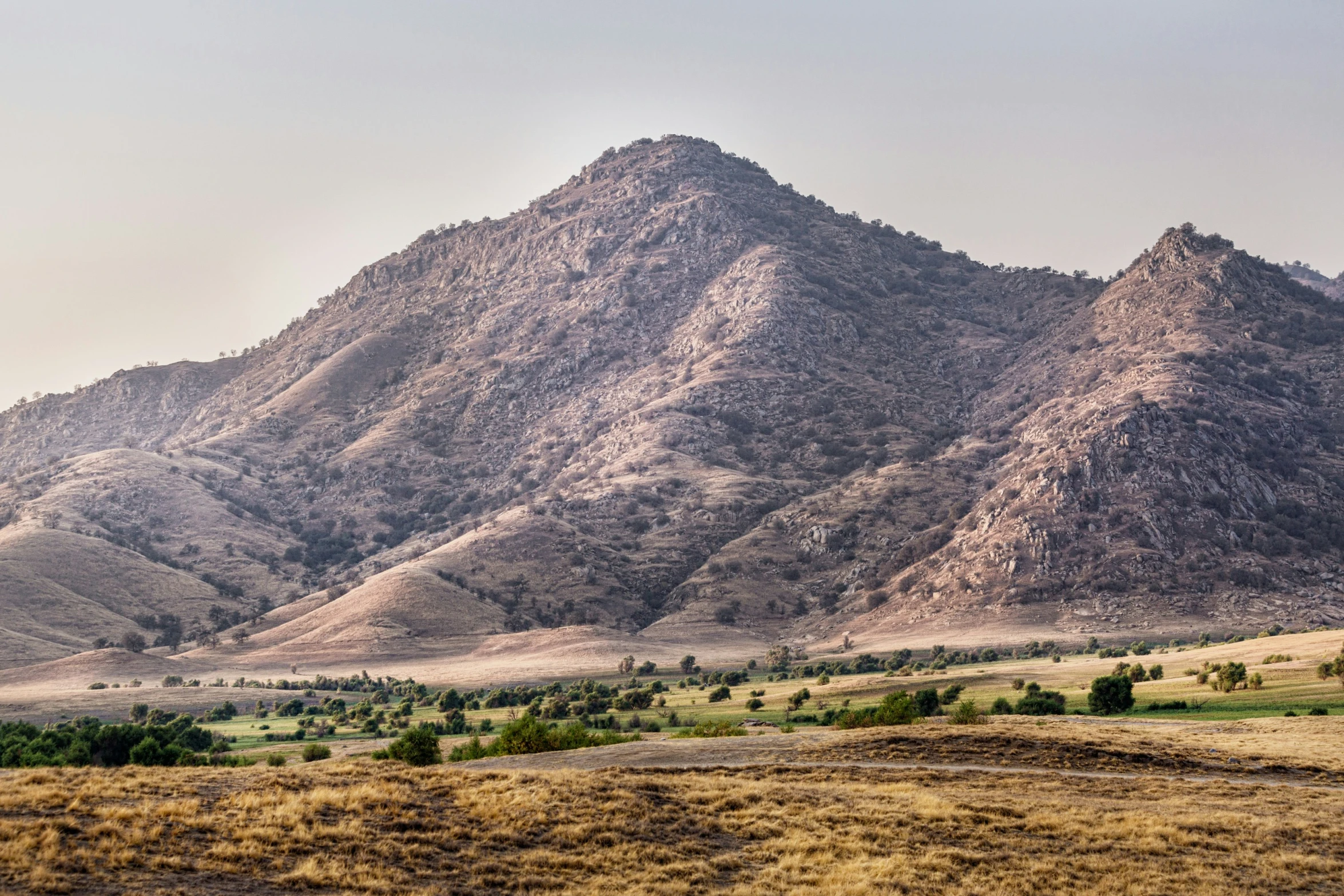 there are some brown mountain peaks and grass