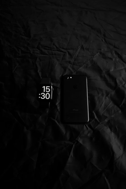 an iphone on a black sheet with a clock