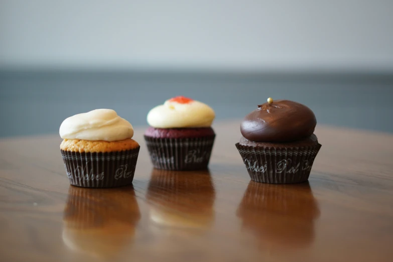 three decorated cupcakes sitting on a table with one missing a bite