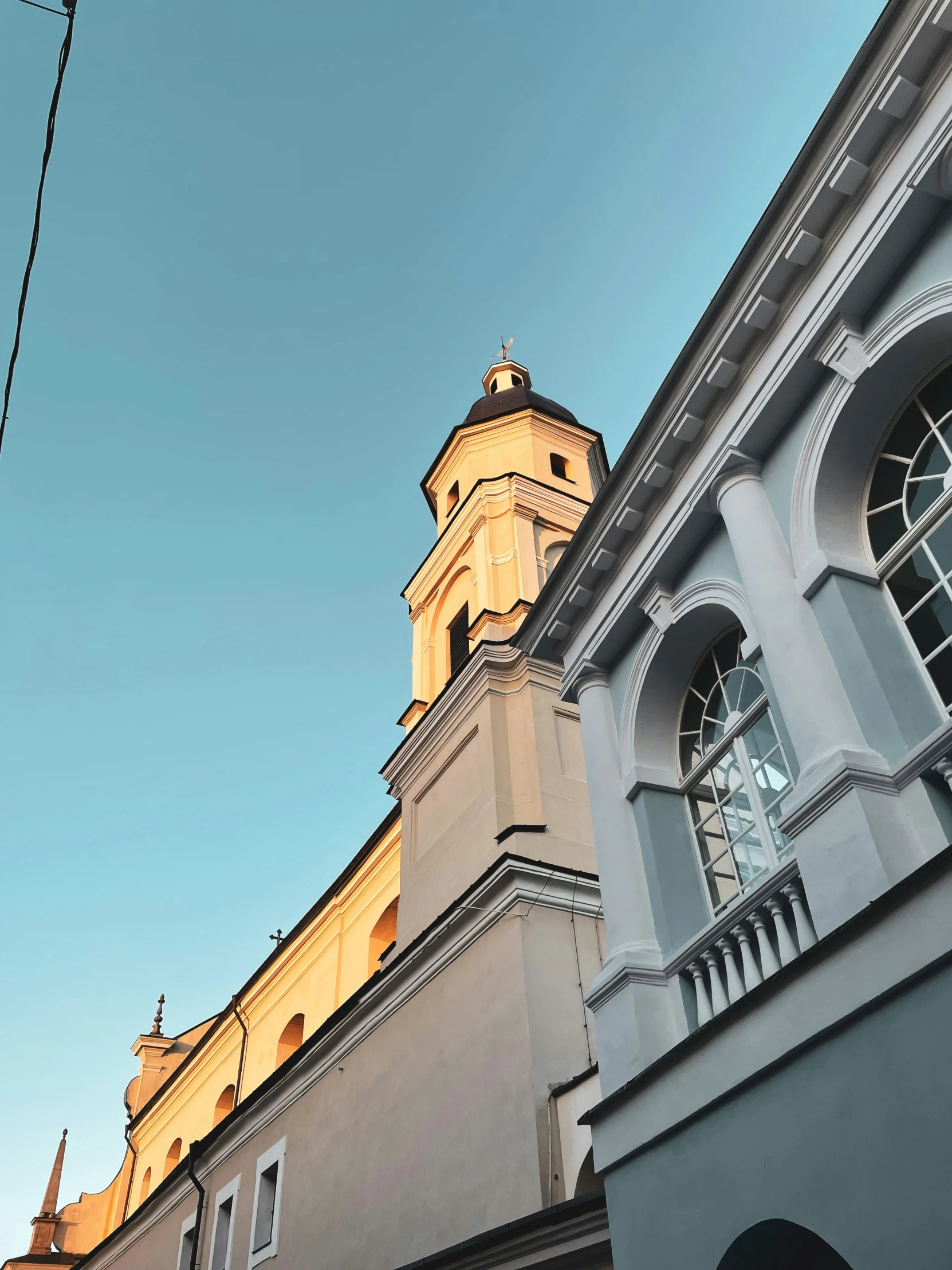 the side of a building with a tower under a blue sky