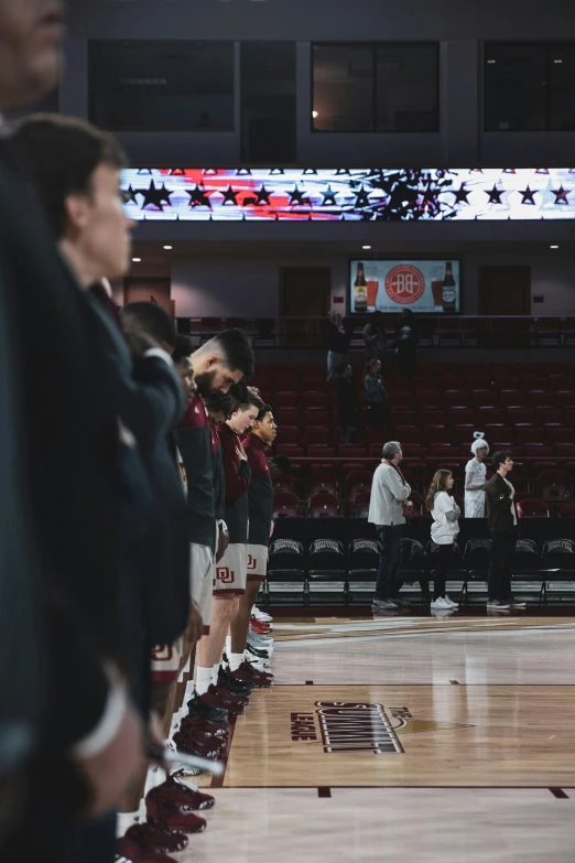 people standing in front of a crowd on a basketball court