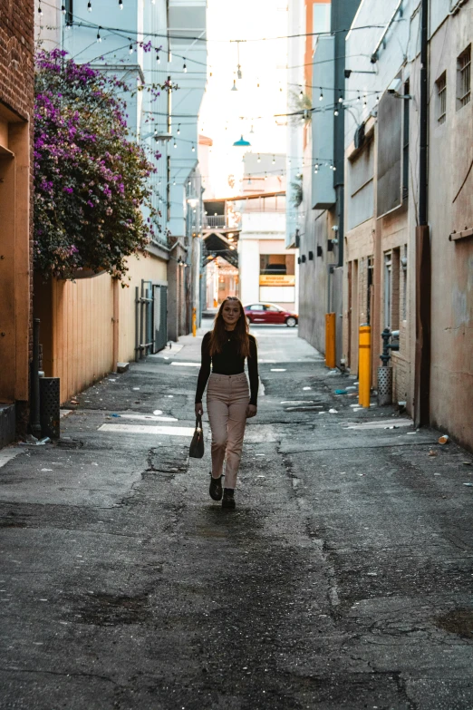 a woman is walking down a narrow street