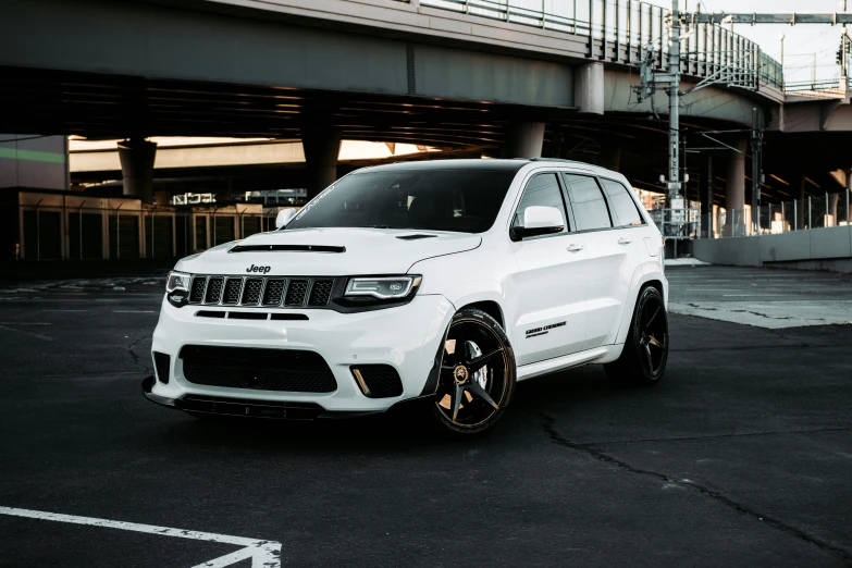 a white jeep parked in a parking lot under an overpass