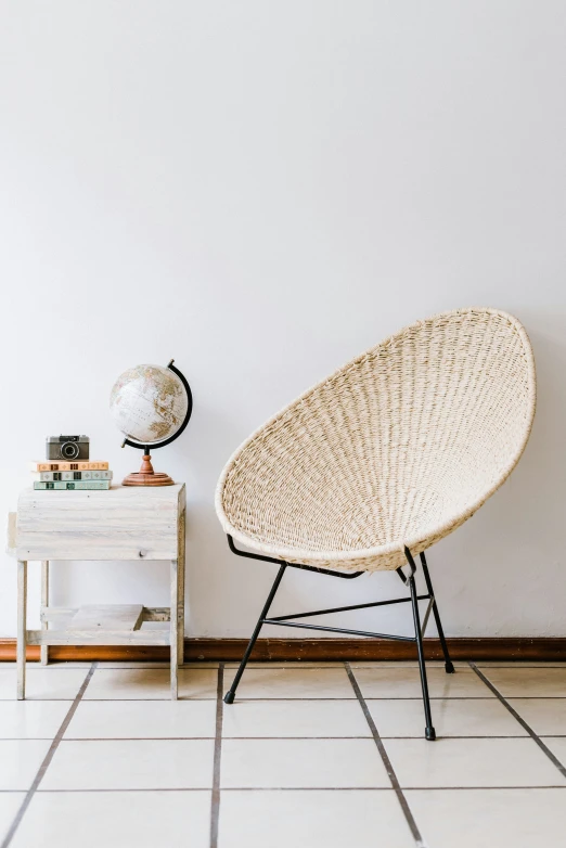 a woven piece of furniture is sitting on the floor in a room with white walls