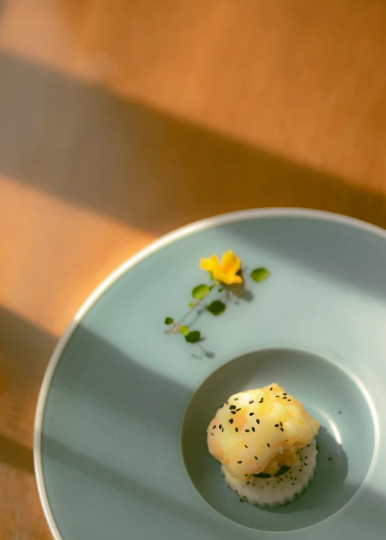 a small plate is placed on a table with a flower and a piece of food in the center