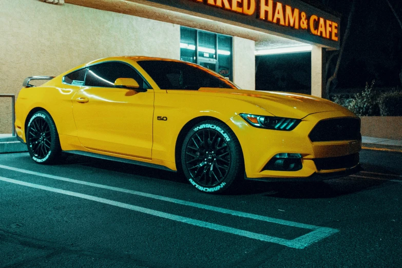 the yellow mustang in front of a building