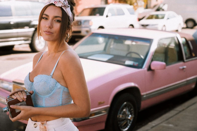 a woman wearing a pink  stands near a pink car