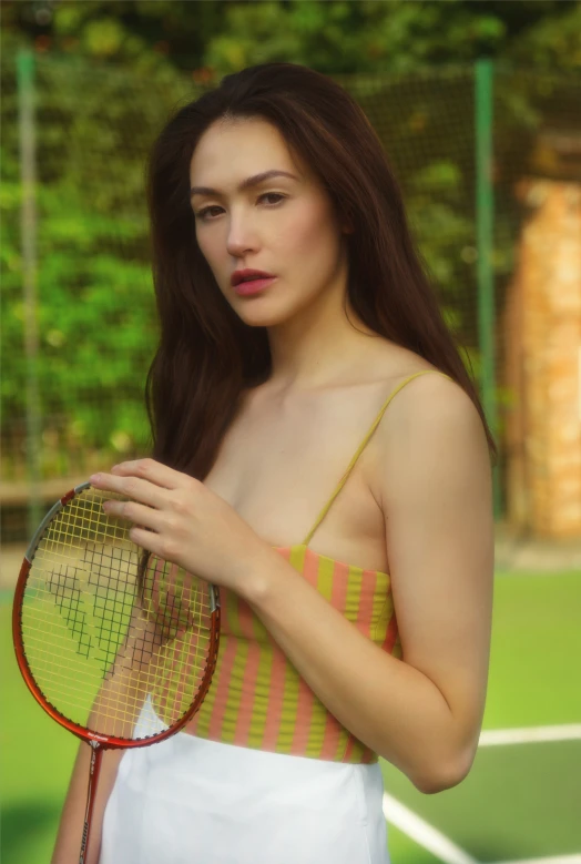 young woman holding tennis racket in front of tree