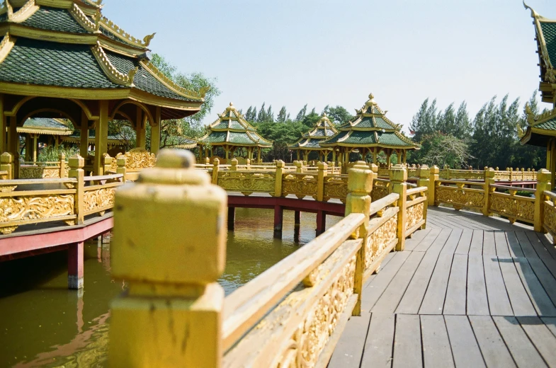 several gold pavilions sitting on a wooden pier