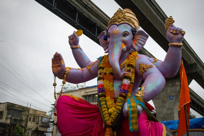the giant statue of an elephant is dressed in pink and orange