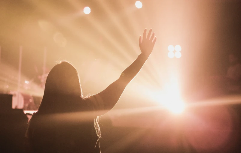 someone with their hand up as the sun shines through