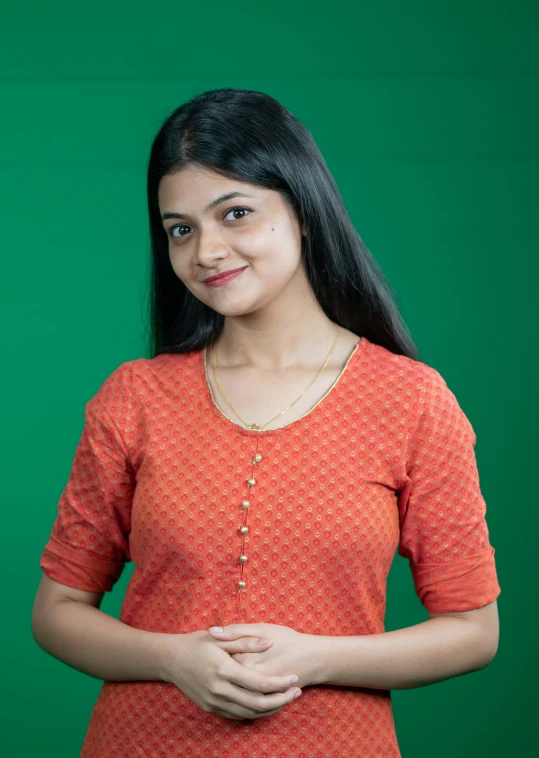 a woman smiling for the camera wearing a bright orange top