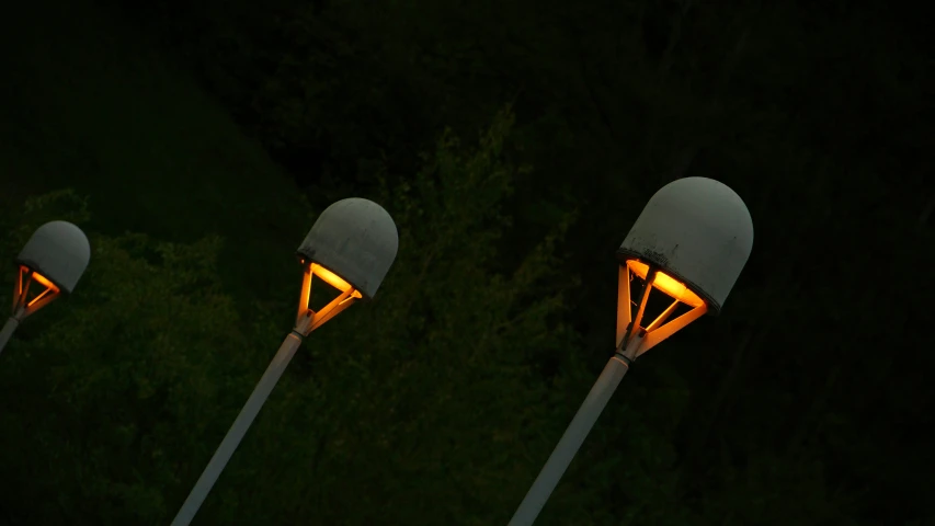 three decorative, metal lights sitting side by side in the dark