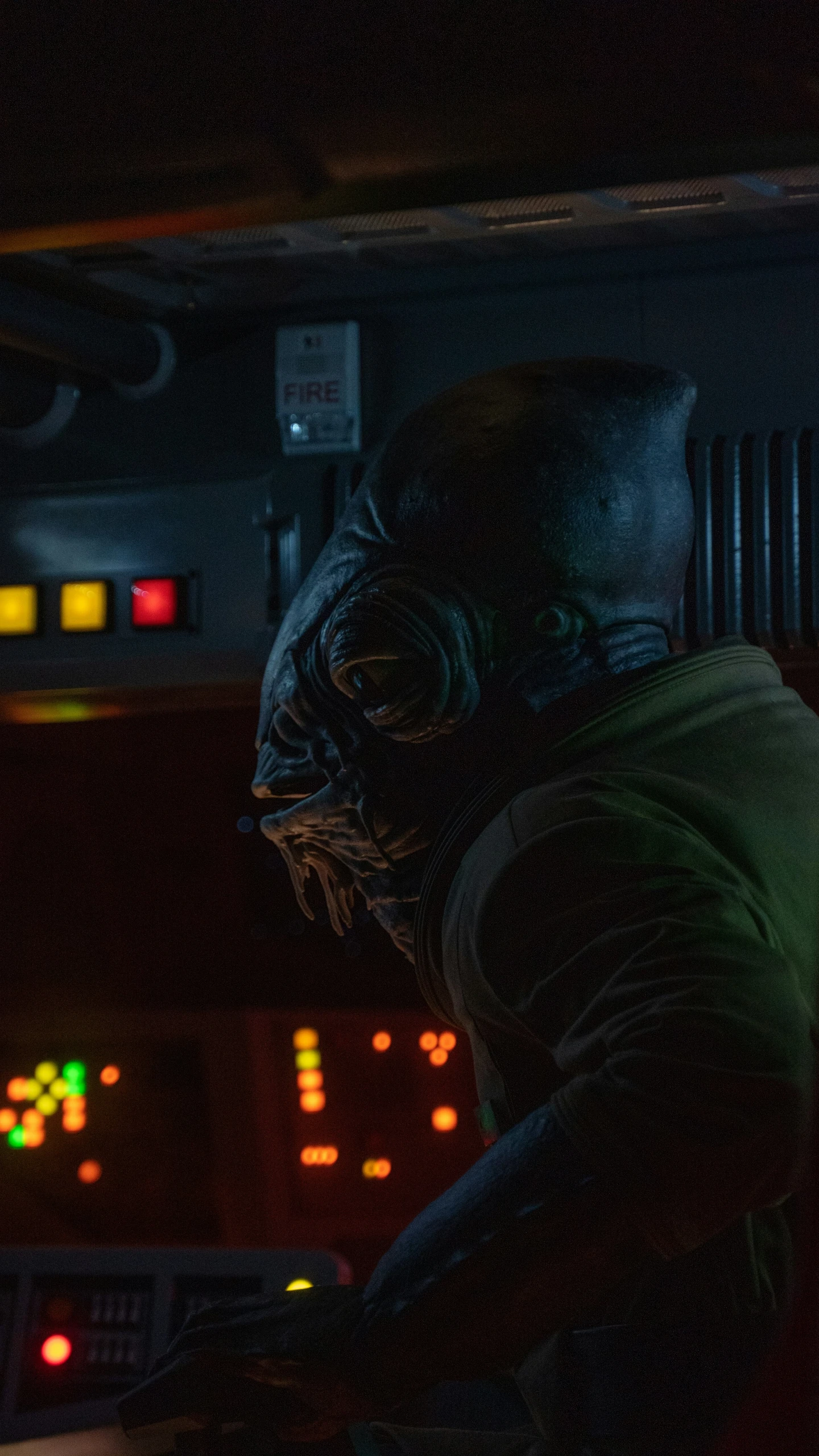 man with head covering sitting at desk in dark