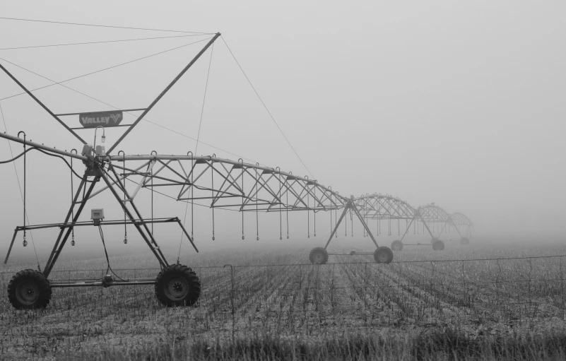 several large farm machinery on the side of a road in the fog