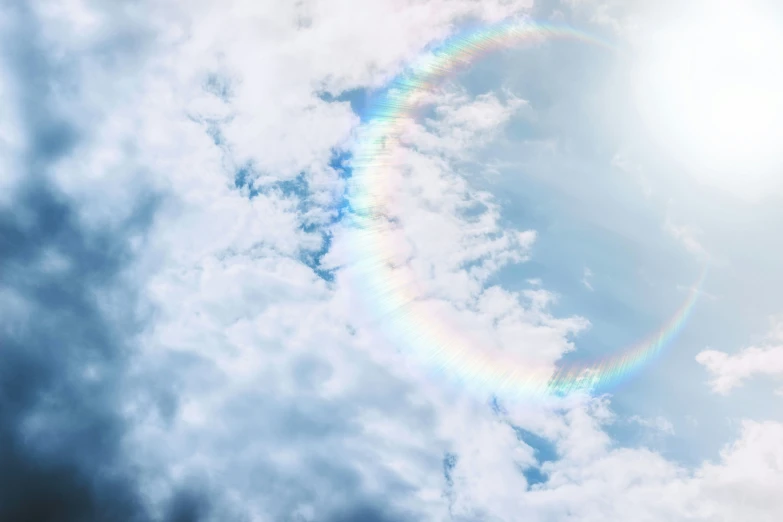 a big rainbow colored circle floating through a blue sky